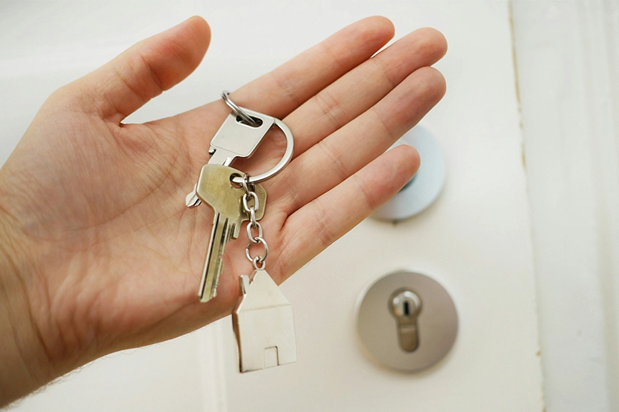 Hand holding keys in front of a door