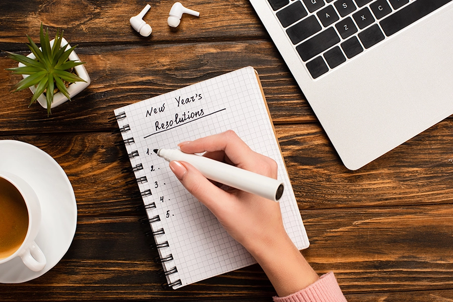 Woman's hand writing new years resolutions on a piece of paper