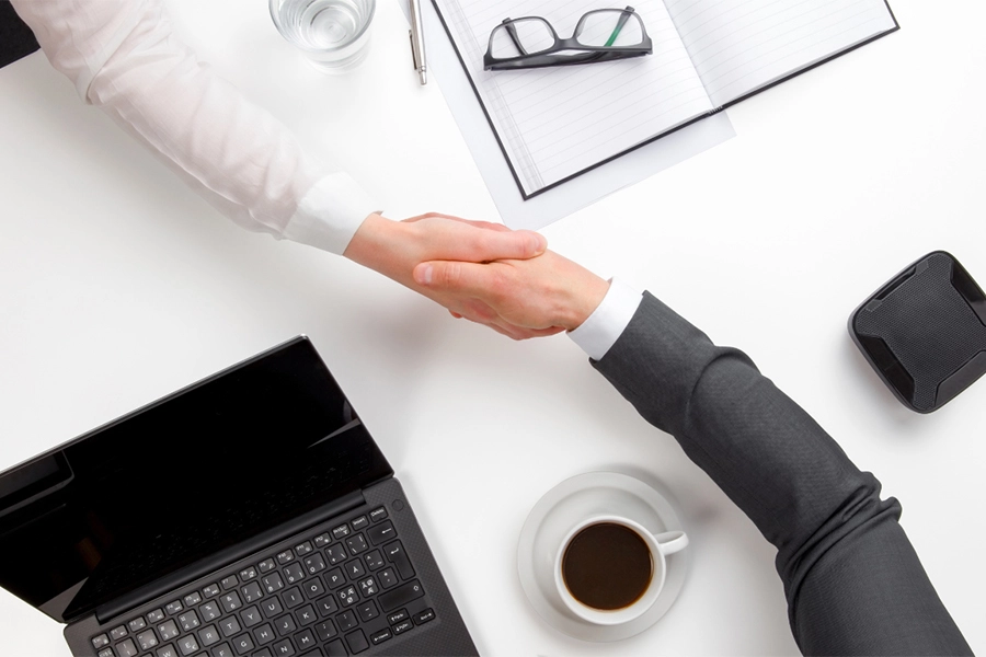 Two men shaking hands over a desk